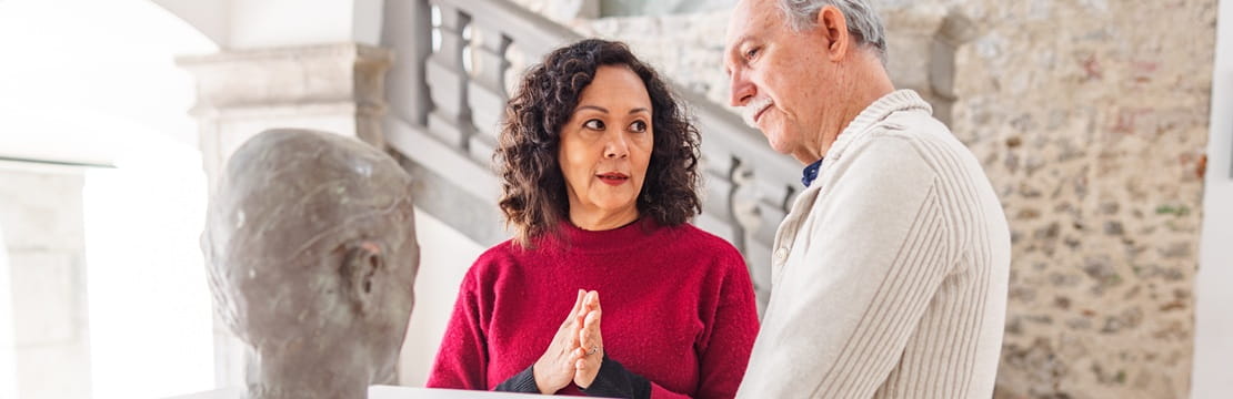 Museum docent guiding a visitor through an exhibit, illustrating how service, creativity, and connection can bring purpose later in life.