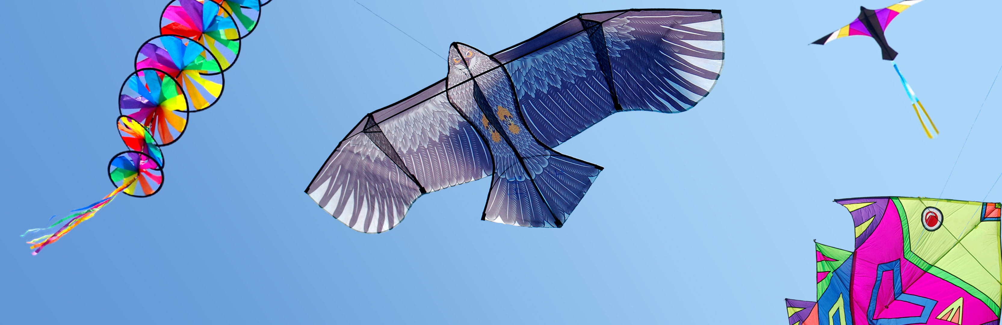 Colorful kites soar across a bright blue sky, symbolizing how embracing playful, childlike activities can support emotional, mental, and physical well-being in adulthood.